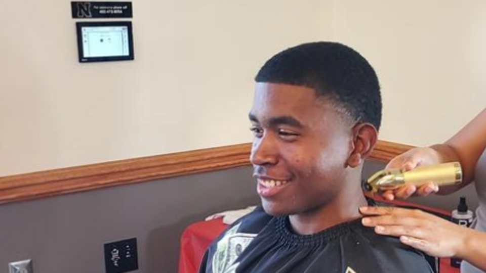 A barber uses clippers to trim hair on a man's neck at Cuts, Convos, & Coffee in 2024.